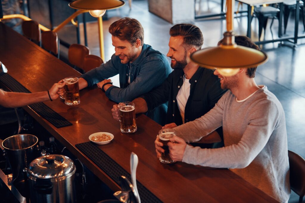 top-view-of-bartender-serving-beer-to-young-men-while-standing-at-the-bar-counter-in-pub.jpg